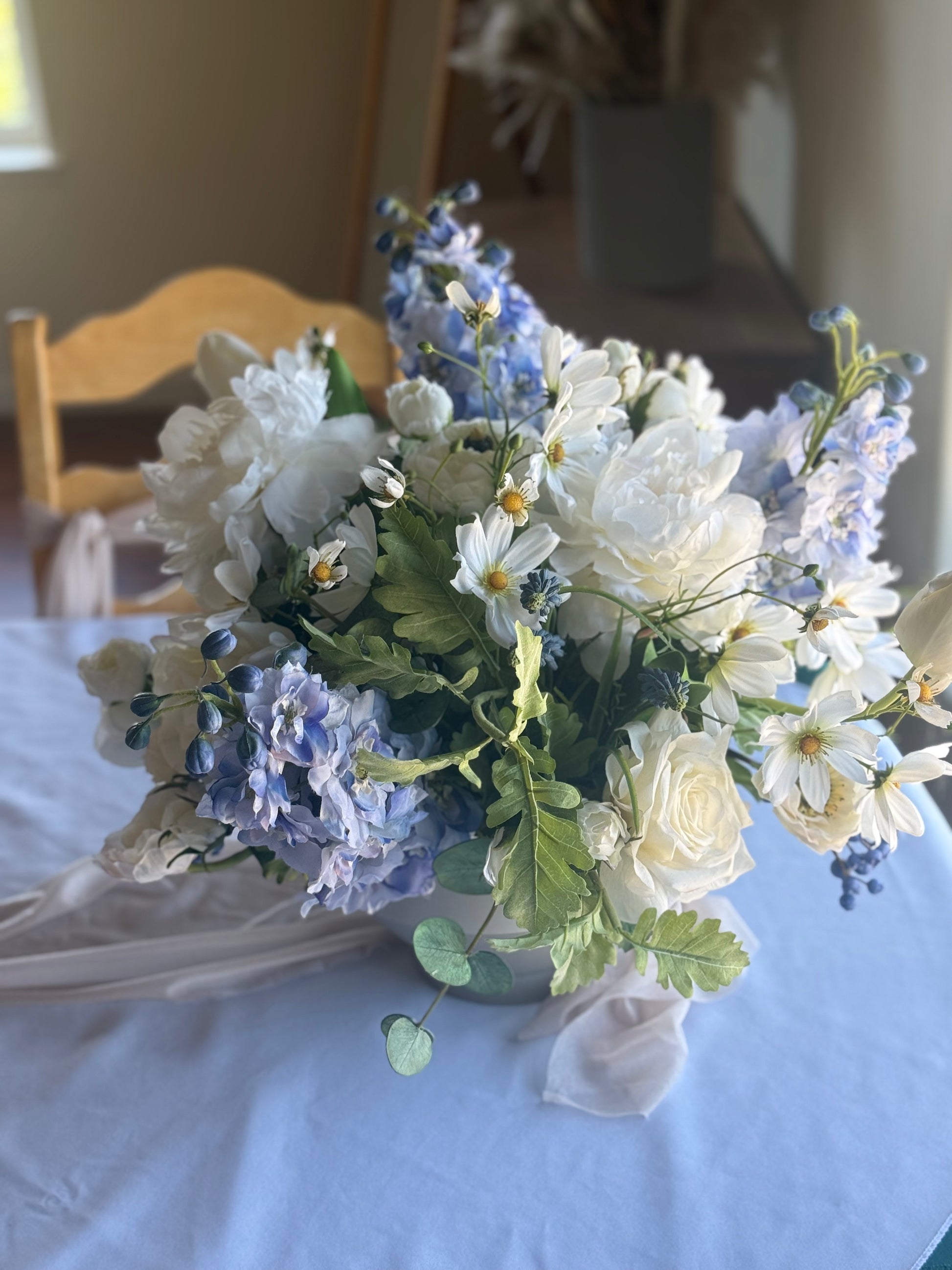 Blue Sunshine centerpiece rental with white peonies, blue hydrangea, blue delphinium, white roses, white cosmos, and lush greenery on blue linen wedding reception table | Reno, Lake Tahoe & Sacramento