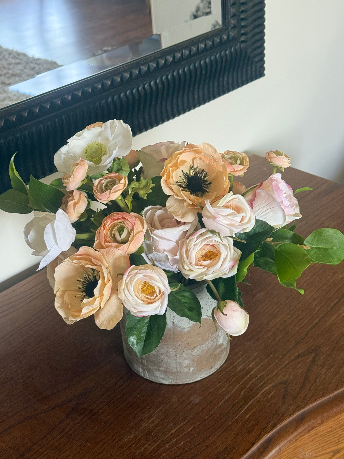 Anemone Blush Garden centerpiece rental with blush and peach anemones, blush ranunculus, white anemones, and lush greenery in rustic concrete vase on dark wood dresser | Reno, Lake Tahoe & Sacramento