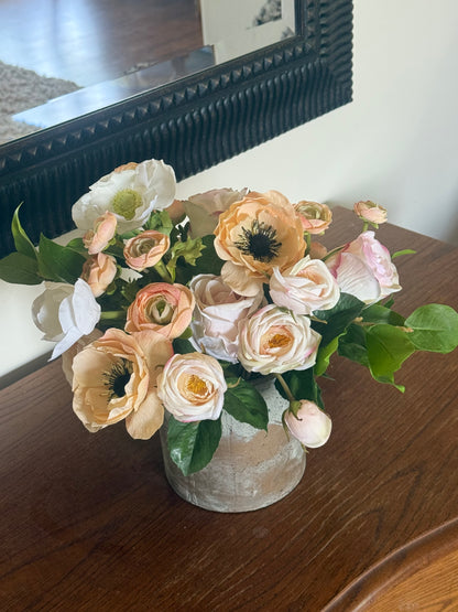 Anemone Blush Garden centerpiece rental with blush and peach anemones, blush ranunculus, white anemones, and lush greenery in rustic concrete vase on dark wood dresser | Reno, Lake Tahoe & Sacramento