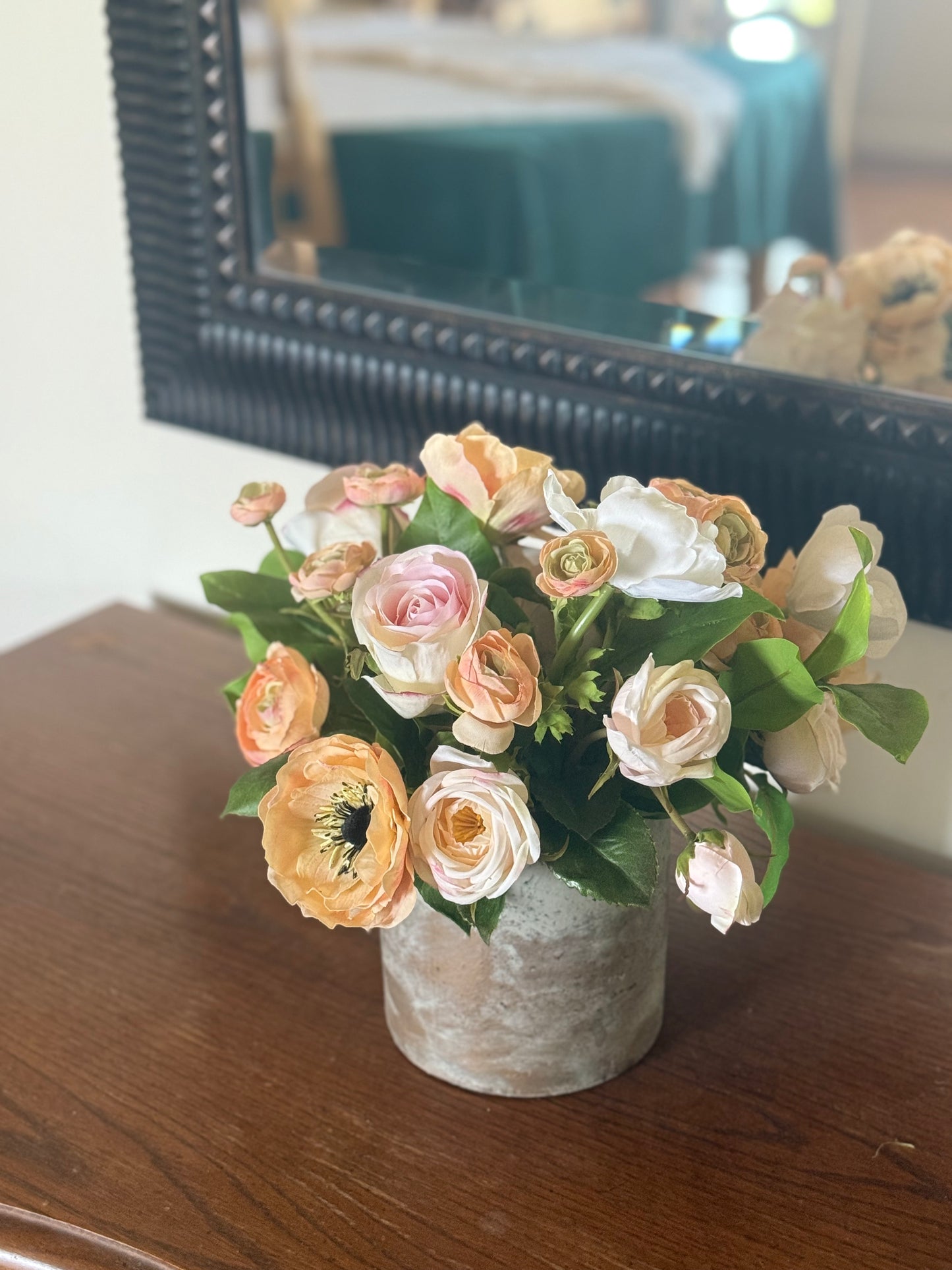 Anemone Blush Garden centerpiece rental with blush and peach anemones, blush ranunculus, and lush greenery in rustic concrete vase on dark wood dresser with ornate black mirror at indoor home setting | Reno, Lake Tahoe & Sacramento