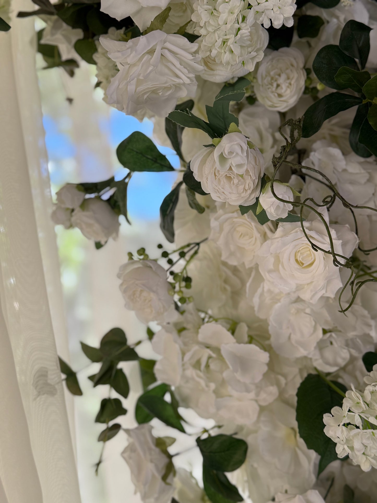 Close-up of Daydream arch rental floral detail showing white garden roses, hydrangea, clematis, and lush greenery with pine tree backdrop | Reno, Lake Tahoe & Sacramento