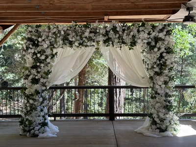 Daydream white floral arch with flowing draping under rustic pavilion wedding rental Timeless Arches Reno NV