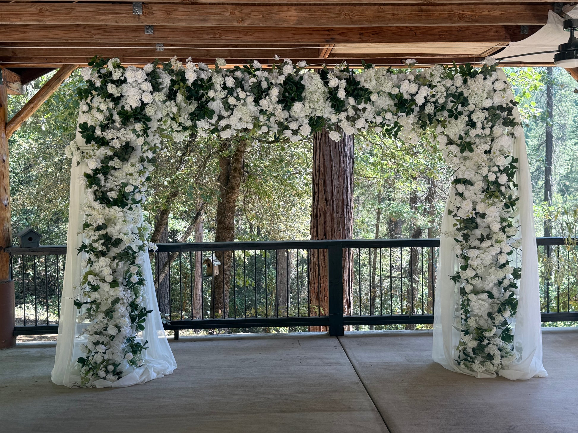 Full Daydream arch rental with white roses, hydrangea, greenery, and flowing white chiffon drapery at outdoor redwood forest wedding venue | Reno, Lake Tahoe & Sacramento