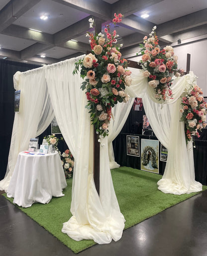 Delicate arch adornment rental with blush and coral roses and white drapery styled on Chuppah rental at indoor wedding expo | Reno, Lake Tahoe & Sacramento