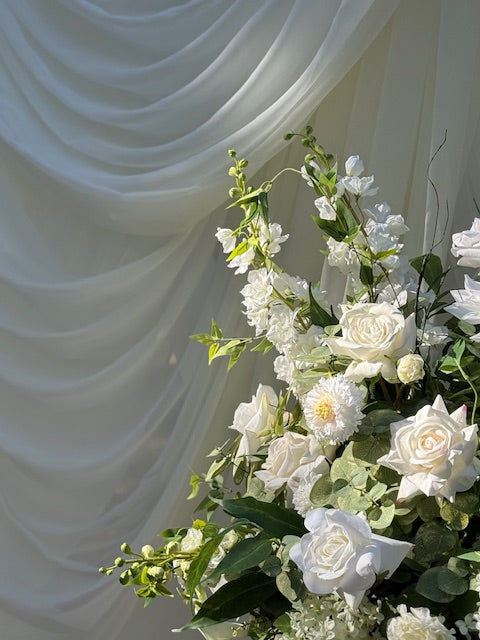 White chiffon drapery rental as ceremony backdrop styled with Enchanted Urn rental featuring white roses, ranunculus, and lush greenery | Reno, Lake Tahoe & Sacramento