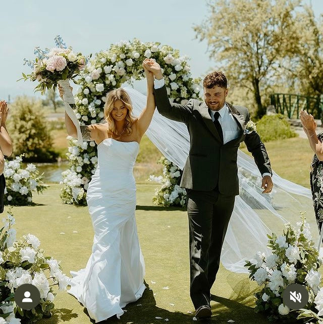 Bride and groom celebrating recessional under Enchanted circular arch rental with white  and peach roses and greenery at outdoor Nevada garden wedding venue with Enchanted aisle flowers | Reno, Lake Tahoe & Sacramento