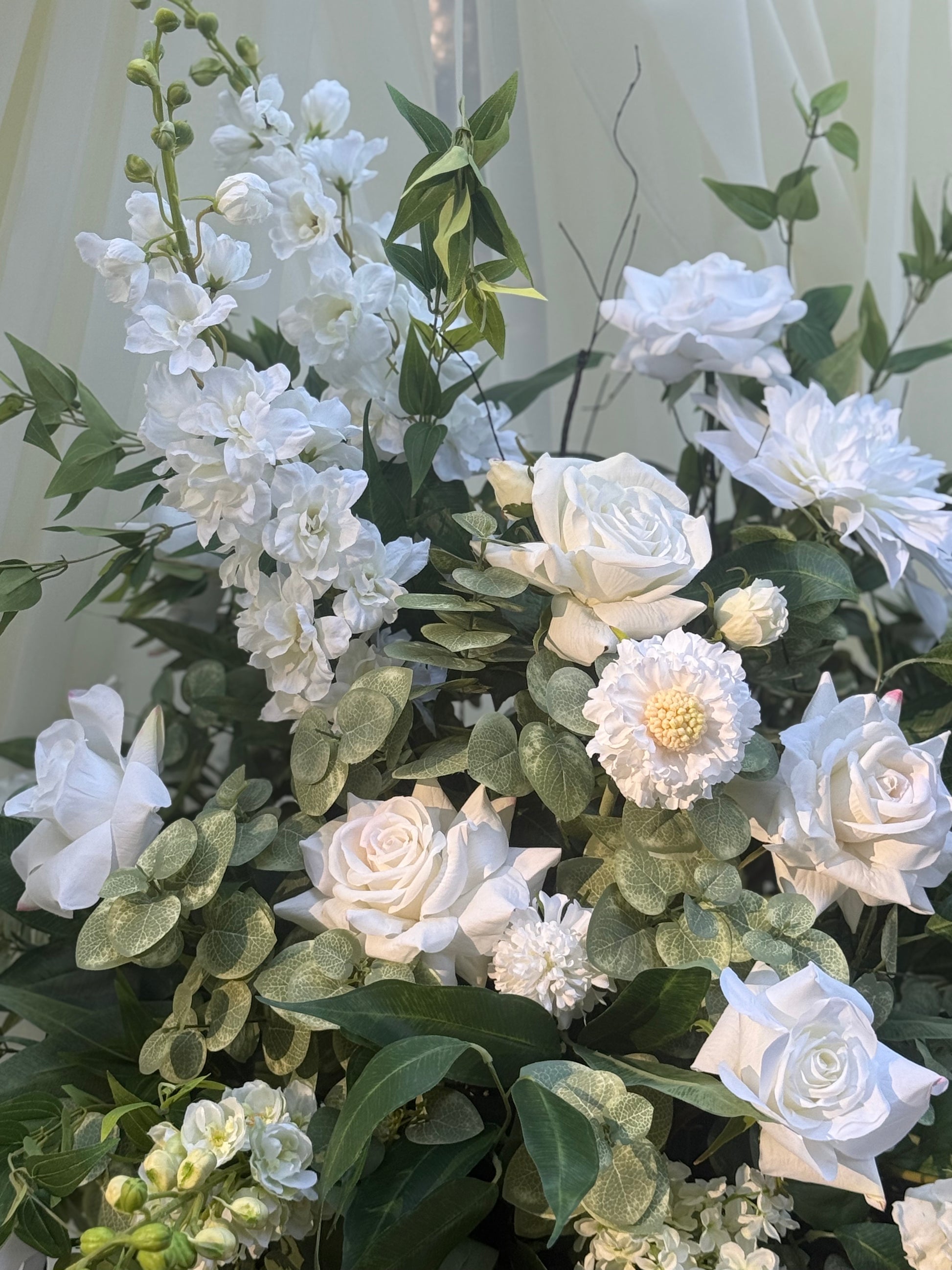 Close-up of Enchanted floral urn rental with white roses, white delphinium, white dahlias, white scabiosa, and lush greenery at indoor wedding venue | Reno, Lake Tahoe & Sacramento