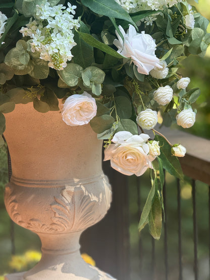 Close-up of Enchanted floral stone urn rental with cascading cream roses, white ranunculus, and eucalyptus at outdoor wedding venue | Reno, Lake Tahoe & Sacramento