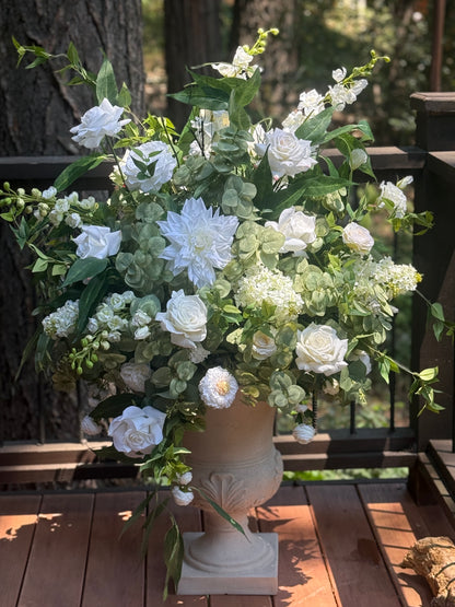 Enchanted floral stone urn rental overflowing with white roses, white dahlias, white hydrangea, white ranunculus, and lush greenery on wood deck at outdoor pine forest wedding venue | Reno, Lake Tahoe & Sacramento