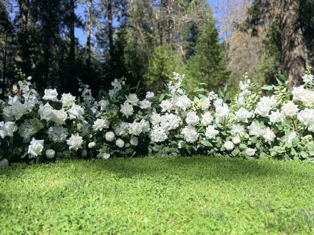 Full row of Enchanted aisle flower rentals lining outdoor pine forest wedding ceremony grass aisle with white roses, white hydrangea, white delphinium, and eucalyptus | Reno, Lake Tahoe & Sacramento

