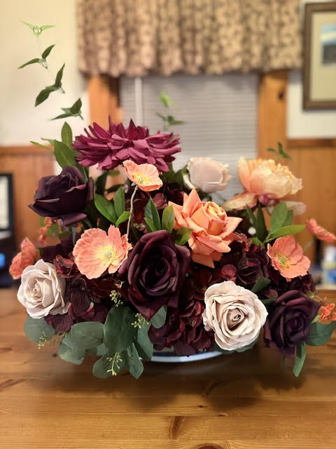 Evermore Centerpiece large arrangement with burgundy dahlia, plum roses, coral poppies and orange roses on wood table