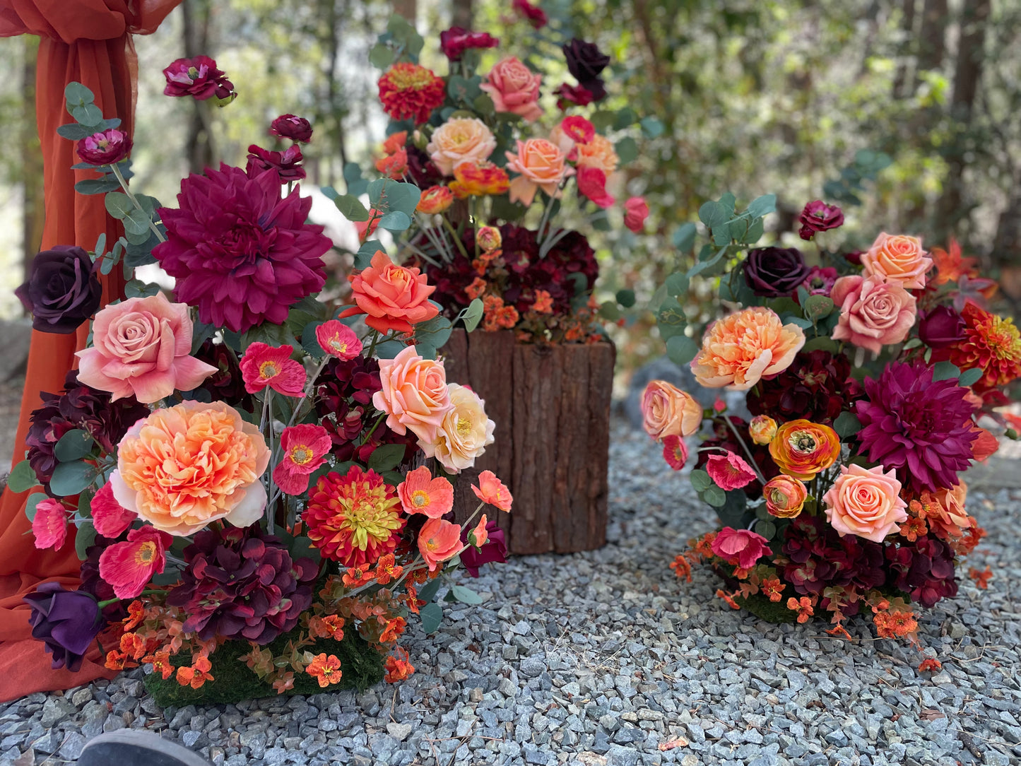 Close-up of 3 Evermore Fall aisle flower rentals with coral garden roses, burgundy dahlias, orange ranunculus, and eucalyptus at outdoor redwood forest wedding | Reno, Lake Tahoe & Sacramento