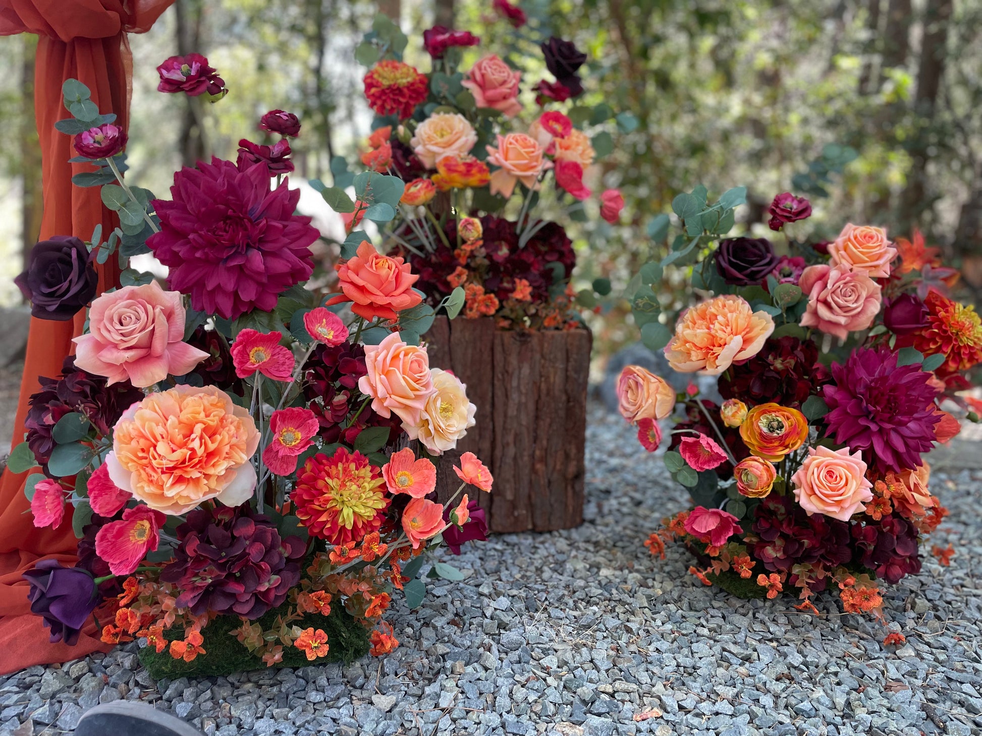 Close-up of 3 Evermore Fall aisle flower rentals with coral garden roses, burgundy dahlias, orange ranunculus, and eucalyptus at outdoor redwood forest wedding | Reno, Lake Tahoe & Sacramento