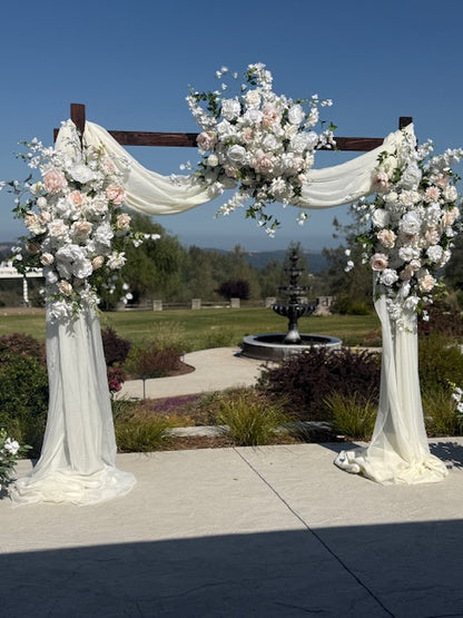 Love Story arch adornment rental with blush garden roses, white drapery, and blue delphinium on rustic wood arch at outdoor hilltop wedding venue with mountain views | Reno, Lake Tahoe & Sacramento

