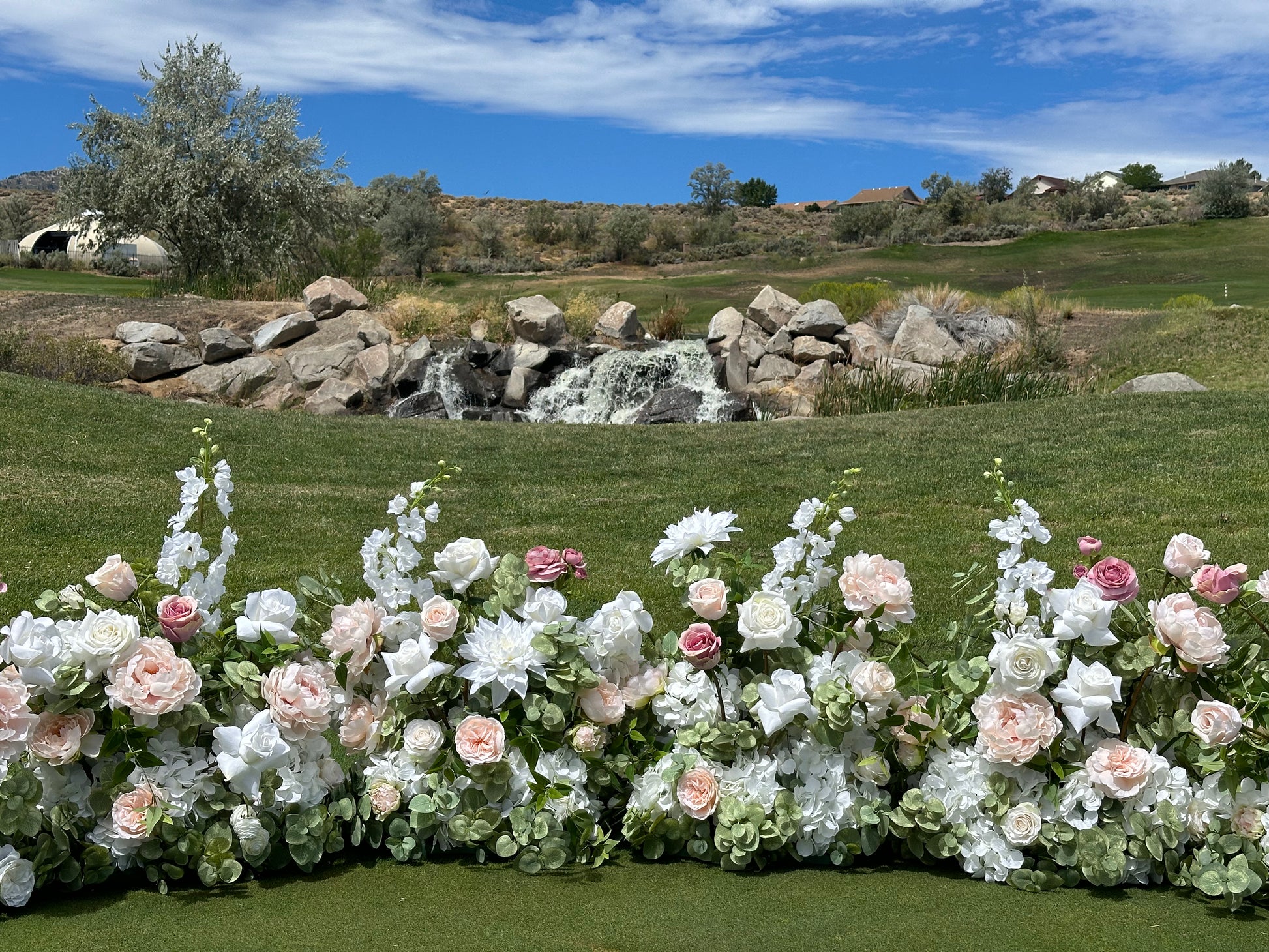 Love Story blush and white aisle flower rental displayed as ground floral installation at outdoor Reno Nevada wedding venue with waterfall backdrop | Reno, Lake Tahoe & Sacramento