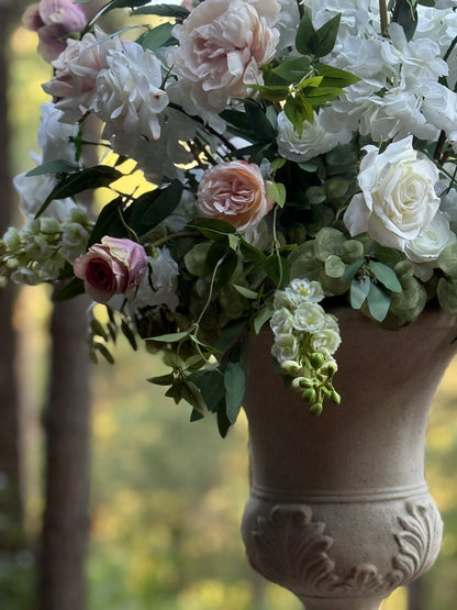 Close-up of Love Story floral stone urn rental with white garden roses, blush peonies, white delphinium, and lush greenery at outdoor pine forest wedding venue | Reno, Lake Tahoe & Sacramento