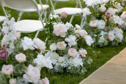  Blush and white aisle flower rental cluster with garden roses, hydrangea, and greenery lining outdoor ceremony aisle with white folding chairs | Reno, Lake Tahoe & Sacramento