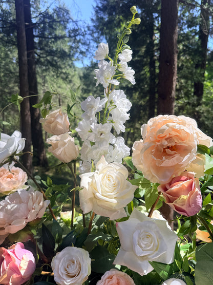 Close-up of Love Story aisle flower rental with white delphinium, cream and peach garden roses, and lush greenery at outdoor pine forest wedding ceremony | Reno, Lake Tahoe & Sacramento
