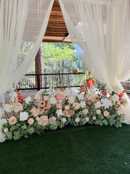 Love Story aisle flower rentals with pop of bright pink styled as lush ground floral installation under white draped canopy with blush, peach, and coral roses, peonies, and snapdragons at forest wedding venue | Reno, Lake Tahoe & Sacramento