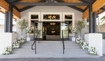 Love Story aisle flower, urns and Eucalyptus trees and pedestal rentals lining venue entrance steps with white and blush ground florals | Reno, Lake Tahoe & Sacramento