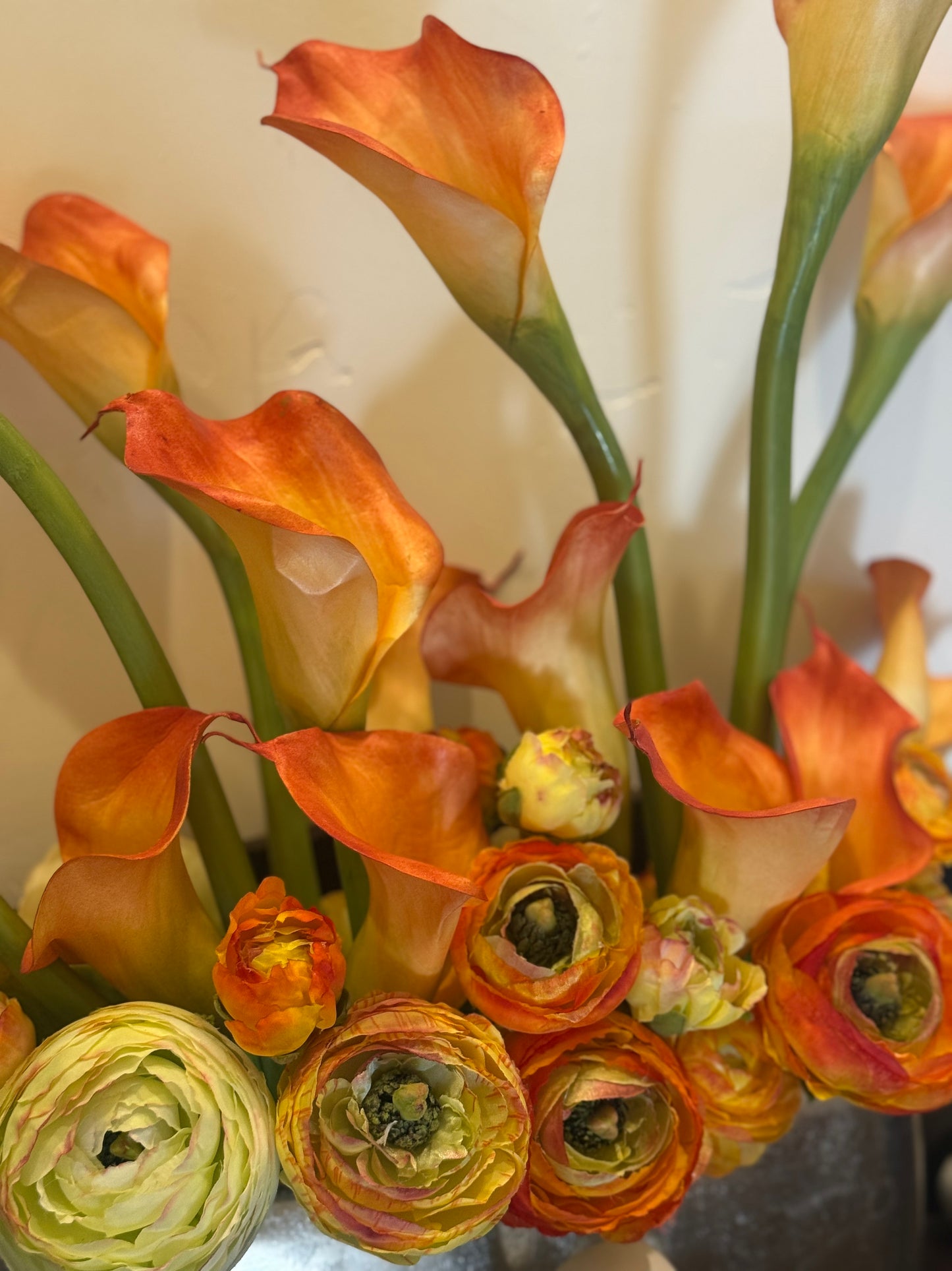Macro close-up of Orange Calla Lily centerpiece rental with orange and yellow calla lilies and orange ranunculus blooms in silver metallic vase | Reno, Lake Tahoe & Sacramento