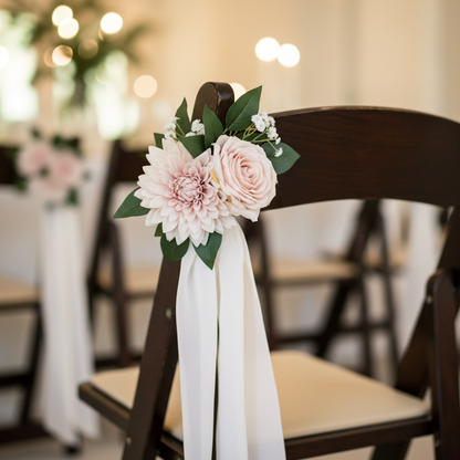 Close-up of Pink Rose & Dahlia Aisle Chair Flower Rental with blush dahlia and blush garden rose cluster with lush green leaves tied with flowing white chiffon ribbon on dark wood folding wedding chair | Reno, Lake Tahoe & Sacramento