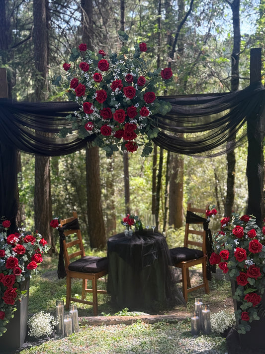 Red rose arch adornment rental with black drapery draped over wooden arch at outdoor forest wedding ceremony with pine tree backdrop | Reno, Lake Tahoe & Sacramento