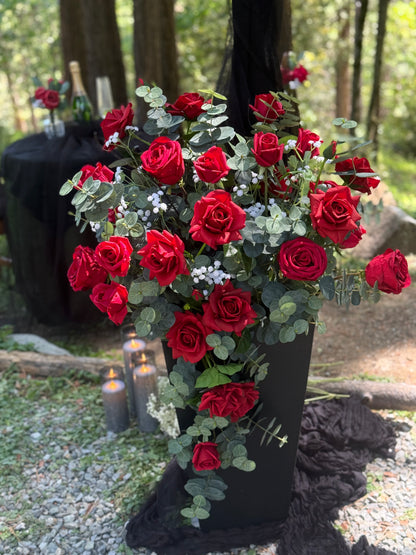 Single black urn rental with cascading red roses, baby's breath, and eucalyptus at outdoor forest wedding ceremony with candles | Reno, Lake Tahoe & Sacramento