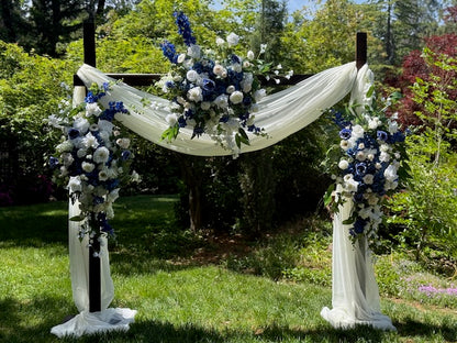 Full Sweet Nothings arch adornment rental with navy blue delphinium, white roses, blue hydrangea, and white drapery on rustic wood arch at outdoor garden wedding | Reno, Lake Tahoe & Sacramento