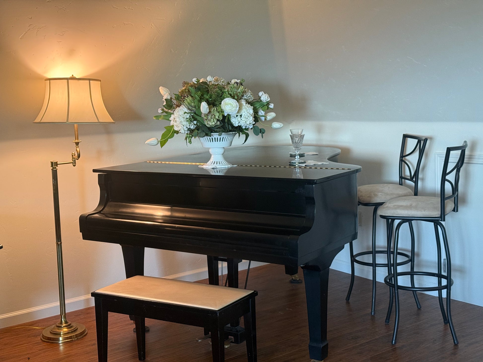 White Garden centerpiece rental with white ranunculus, white hydrangea, white tulips, artichoke blooms, and lush greenery in white lattice compote vase displayed on grand piano at elegant indoor home setting | Reno, Lake Tahoe & Sacramento