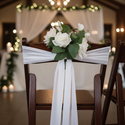 Close-up of White Rose Aisle Chair Flower Rental with white rose cluster and lush green leaves tied with flowing white chiffon ribbon on dark wood folding wedding chair at elegant indoor venue | Reno, Lake Tahoe & Sacramento