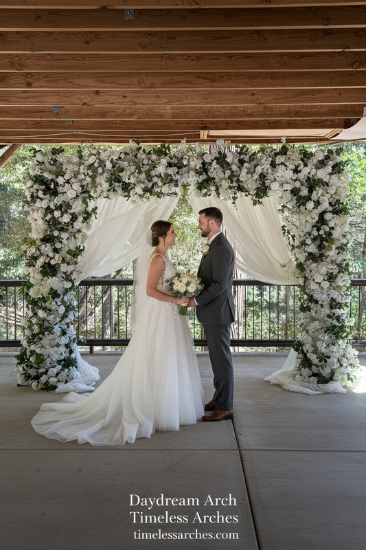 Couple exchanging vows under Daydream arch rental with white roses, hydrangea, and lush greenery at outdoor redwood forest wedding venue | Reno, Lake Tahoe & Sacramento